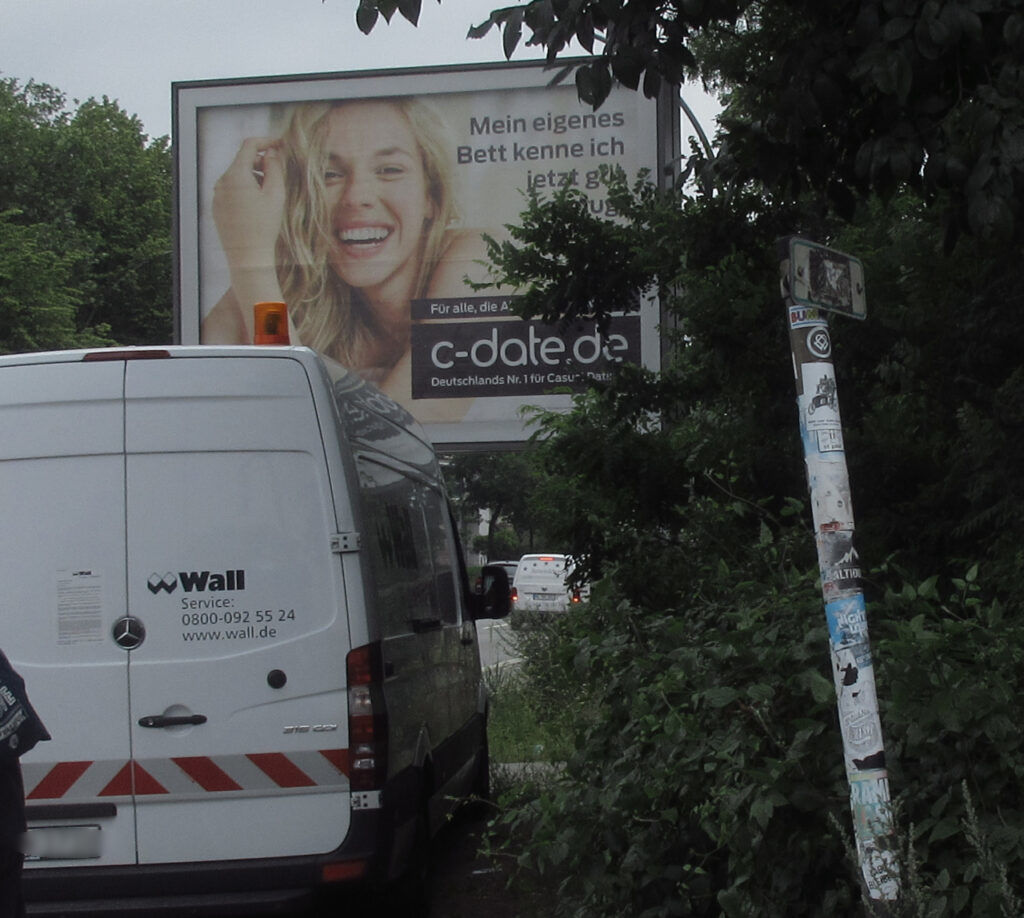 Ein Transporter von Wall (Service: 0800-092 55 24) vor einer großformatigen Zwangsglotze, Rentzelstraße / Schröderstiftsweg, mit Werbung mit einem blonden Model für ein Seitensprungportal.