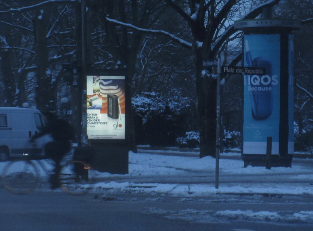 Werbeglotze von Decaux mit Glo und Litfasssäule von Stroeer mit IQOS bei Morgengrauen.
