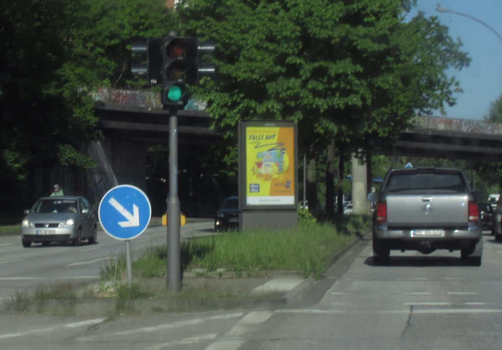 Werbeglotze von JCDecaux auf dem Mittelstreifen neben einer Ampel. Gleiches Auto wie auf dem vorigen Foto.